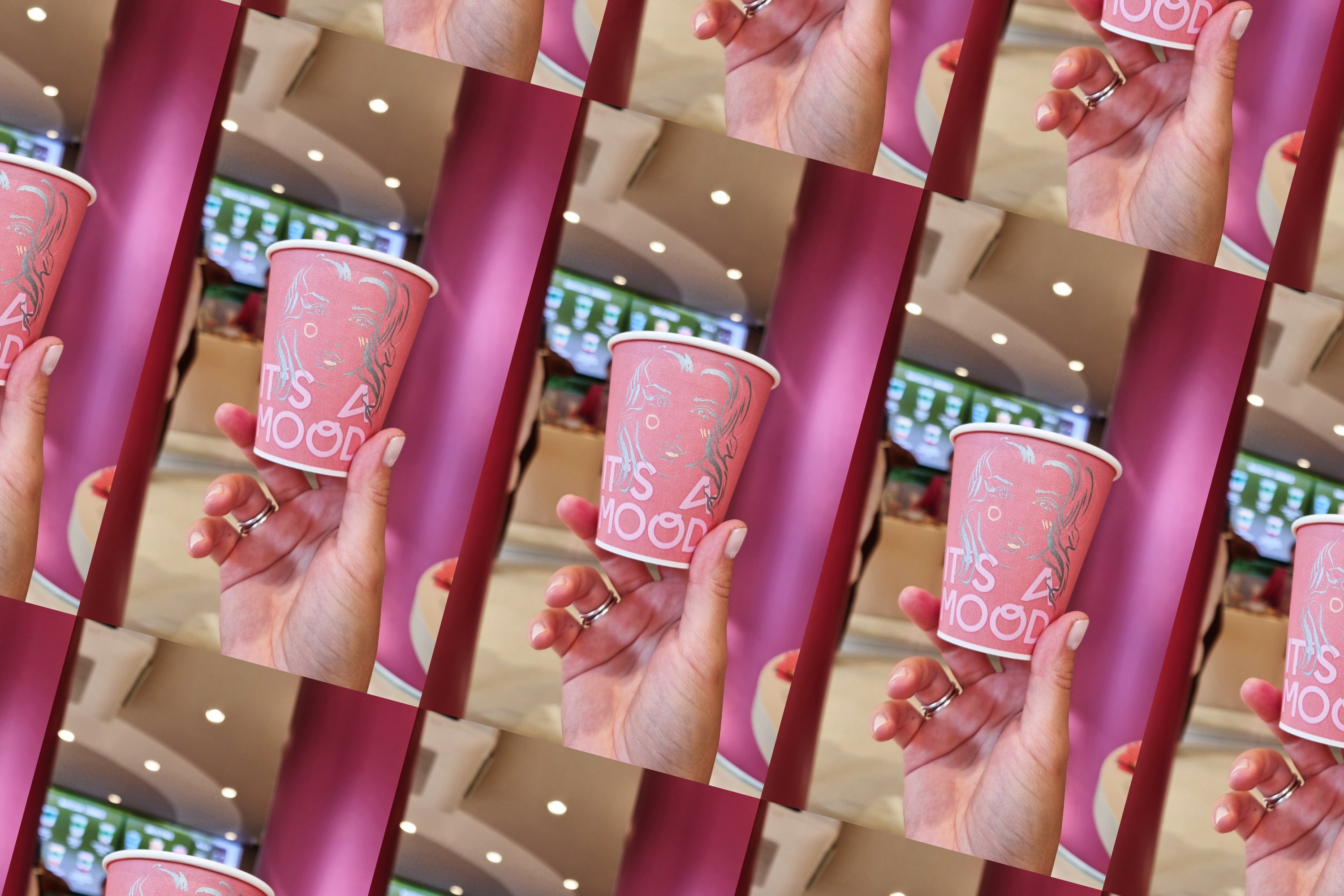 Hand holding a pink 'It's a Mood' cup hand-illustrated with a woman's portrait at the Cinnamood live cup illustration activation